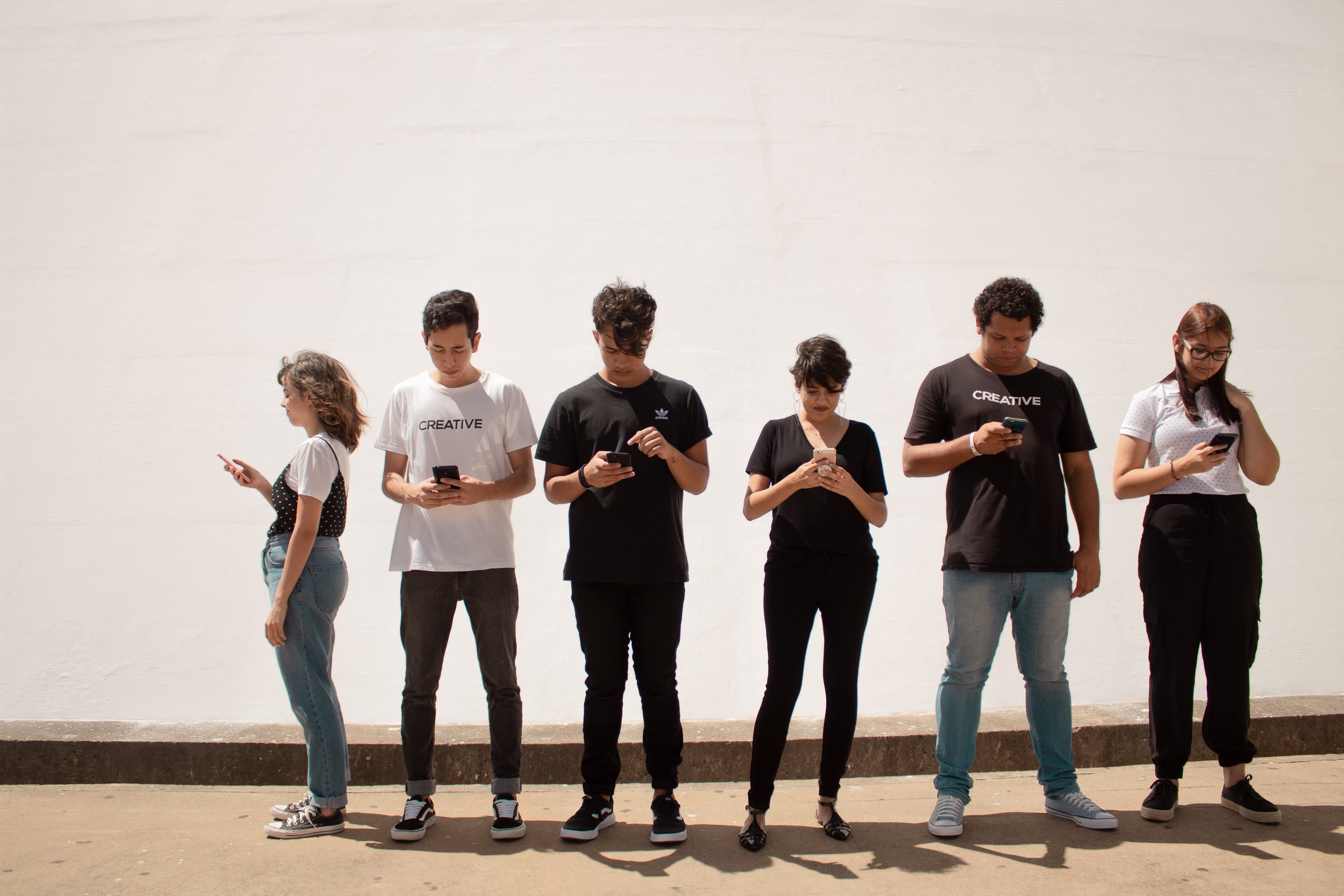 students standing in a line texting 